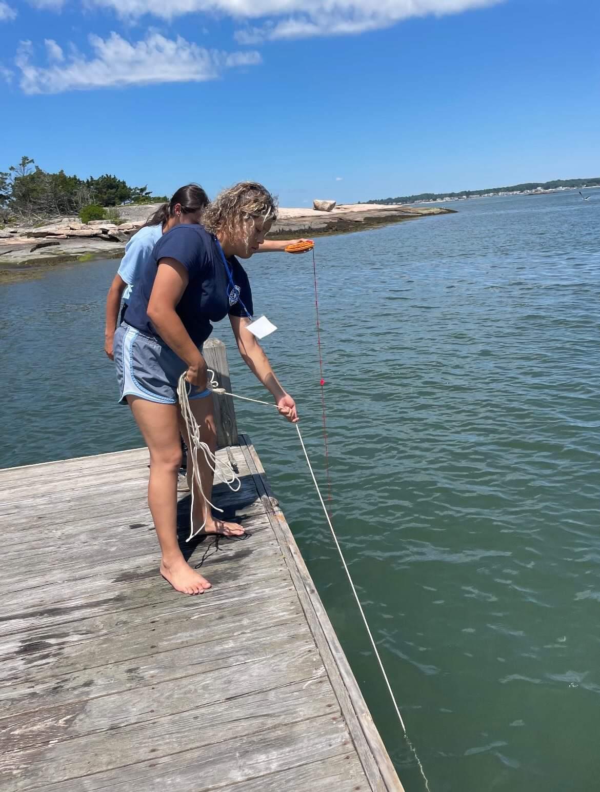 Woman on pier holding rope in the water.